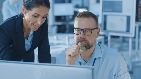 Female Chief Engineer Talks with Electronics Specialist, Explaining Things Stock Footage 105369258