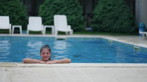 Female child exit out of pool water, smiling and enjoying herself. The pool i Video stock 335603143