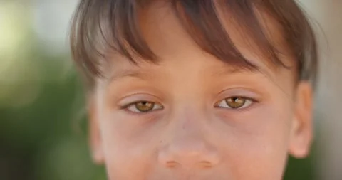 Female child facing camera, shifting gaze and blinking while sun and breeze Stock Footage 344948440