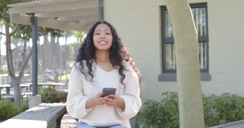 Female child looking down at smartphone, sitting on bench, reading aloud and Stock Footage 340655849
