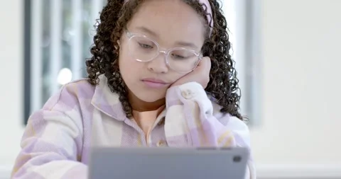 Female child looking up, settling and resting head while working on tablet at Stock Footage 341062653