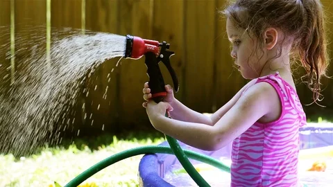 A female child plays with a back yard water hose in summer Stock Footage 112890599