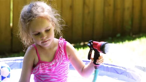 A female child plays with a back yard water hose in summer Stock Footage 112891213