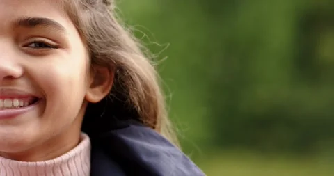 Female child smiling, tilting head in woods with breeze shifting hair in navy Stock Footage 336844404