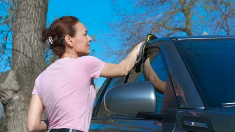 Female cleaning auto in yard Stock Footage 325080484