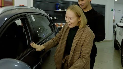 Female client examining car specifications document in the showroom Stock Photos
