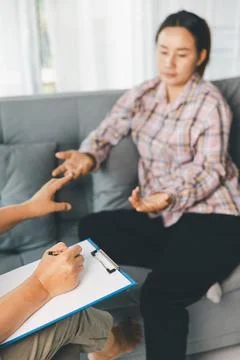 Female client explains feelings with open hands while therapist writes note.. Stock Photos