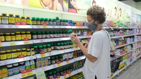 Female client in face mask choosing health and beauty supplements for immune Video stock 166820006