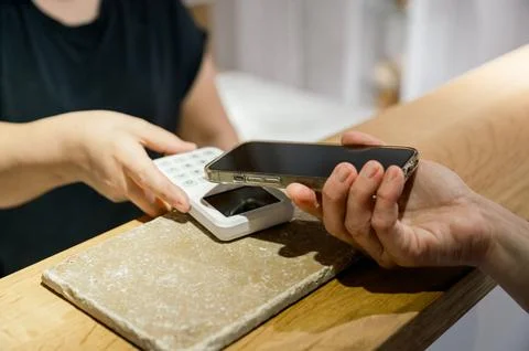 Female client making contactless payment at counter in a shop Stock Photos