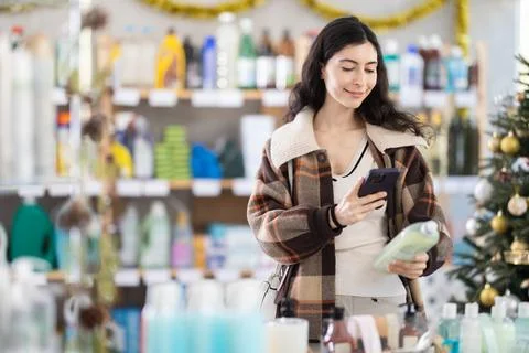 Female client scanning QR code on package dishwashing detergent Stock Photos