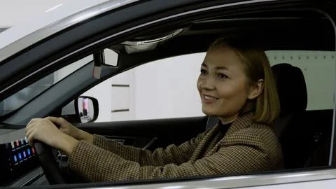 Female client smiling while driving a car in the showroom Stock-Fotos