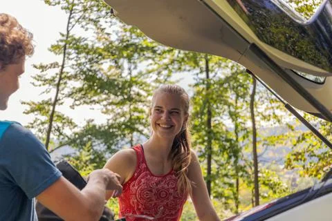 Female climber laughing while taking gear out of the car Stock Photos