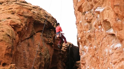 Female climber rappells down red cliffs Stock Footage 99311991