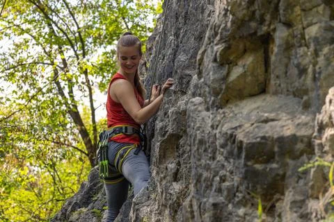 Female climber smiling while climbing in the rock wall Stock Photos