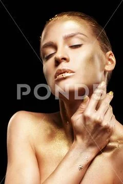 Female with closed eyes and hands near face. Golden girl on black background Stock Photos
