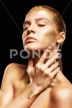 Female with closed eyes and hands near face. Golden girl on black background Stock Photos