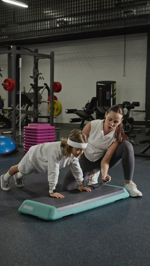 Female Coach Timing Boy Doing Plank Exercise on Step Platform Stock Footage 343386182