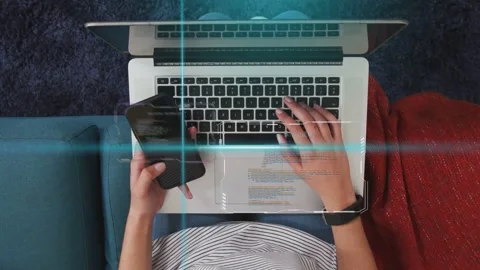 Female coder typing while swiping phone and tilting it, revealing code for Stock Footage 334465933