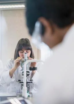 Female college student using microscope conducting scientific experiment in 写真素材