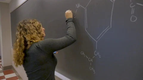 Female college student using a smart phone while writing on a chalkboard Stock Footage 102867319