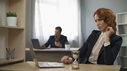 Female company worker typing on laptop, hourglass trickling, devotion to work Stock Footage