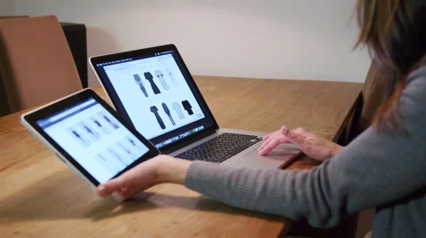 Female comparing prices on ipad and laptop in online store Stock Footage 44758997
