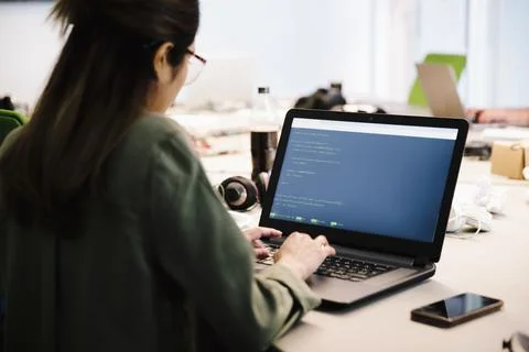 Female compute programmer coding at laptop in office Stock-Fotos
