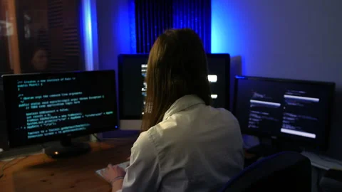 Female computer programmer programming code at night in a dark office Stock Footage 253492686