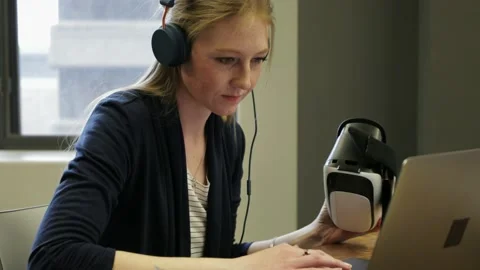 Female computer programmer programming virtual reality simulator at laptop Stock Footage 220345263