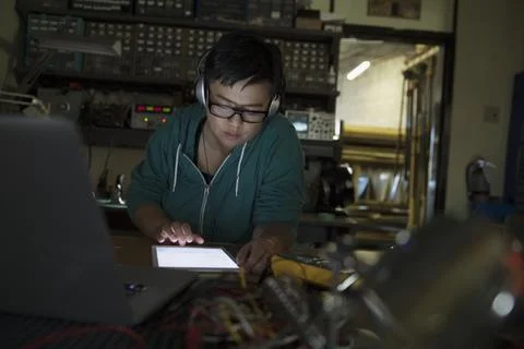 Female computer programmer working using digital tablet wearing headphones in da Foto stock