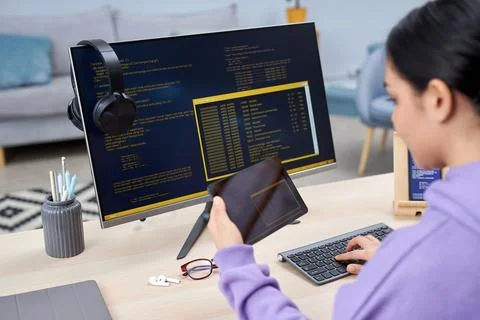 Female computer programmer writing code for mobile devices at desk Stock Photos