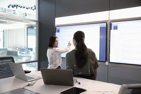 Female computer programmers reviewing code at touch screen in conference room me Foto stock