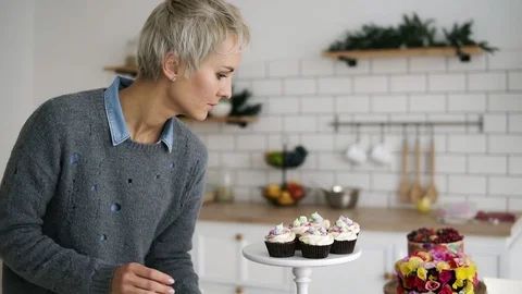 Female confectioner in her kitchen with self made muffins and cakes. Fancy Stock Footage 101149152