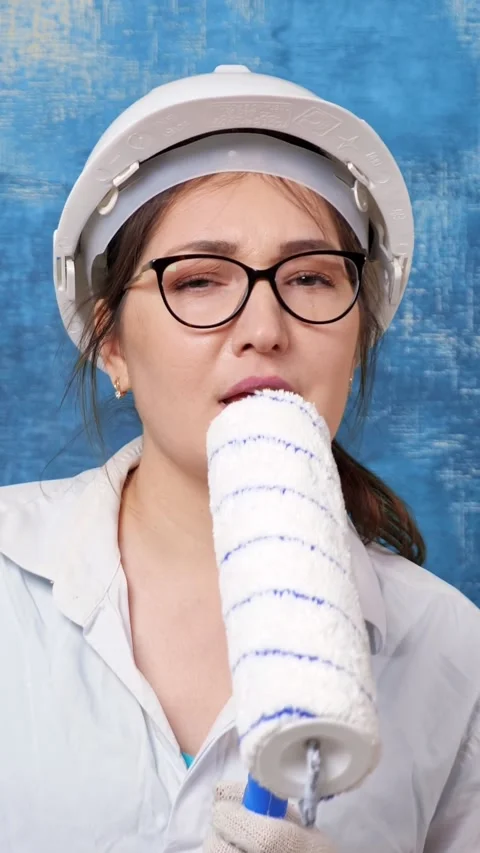 Female construction worker in a hard hat and glasses joyfully singing into a Stock Footage 342904506