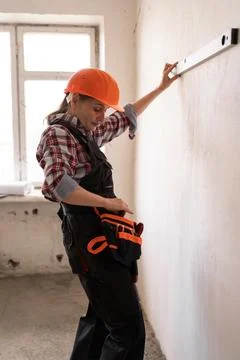Female construction worker measuring wall with level Stock Photos