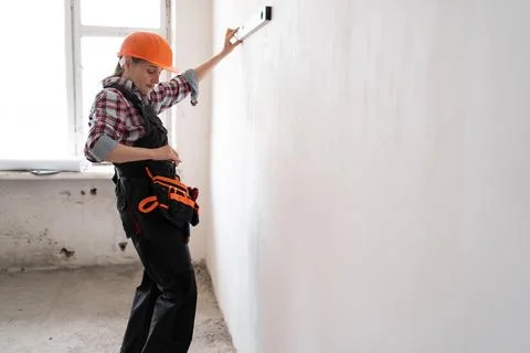 Female construction worker or builder wearing protective helmet uses spirit l Stock Photos