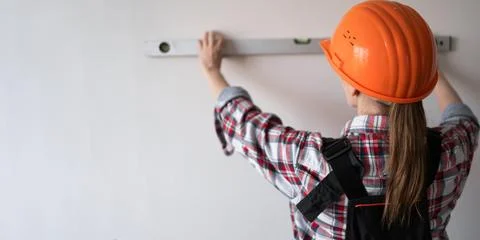 Female construction worker or builder wearing protective helmet uses spirit Stock Photos