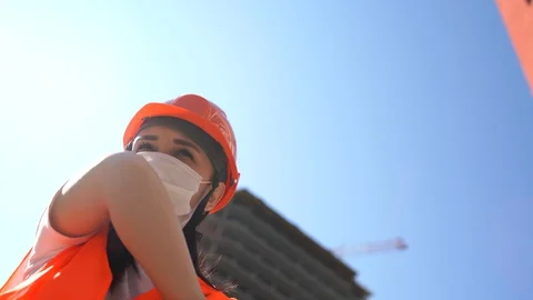Female construction worker in overalls and medical mask coughing in elbow on Stock Footage 129571208