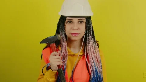 Female construction worker in overalls with hammer on yellow background in Stock Footage 172335200