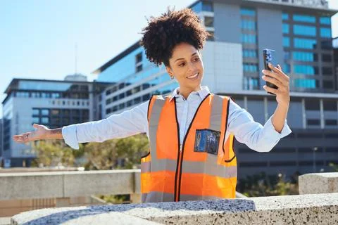 Female Construction Worker Taking a Selfie on Site in Bright Safety Vest Foto stock