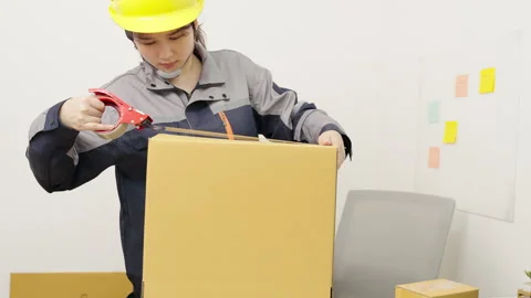 Female construction worker is using adhesive tape to seal or pack boxes Stock Footage 327847835