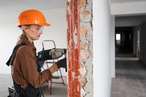 Female construction worker using hammer drill. Builder woman with pneumatic.. Stock Photos