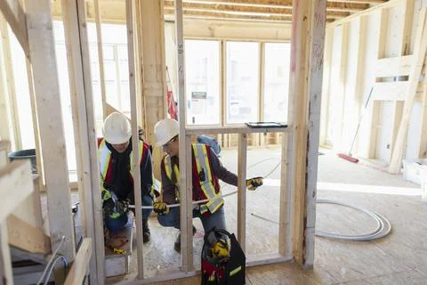 Female construction workers installing pipe in new house Stock Photos