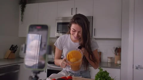 Female content creator taking selfie video cooking in kitchen 库存影片 220753634