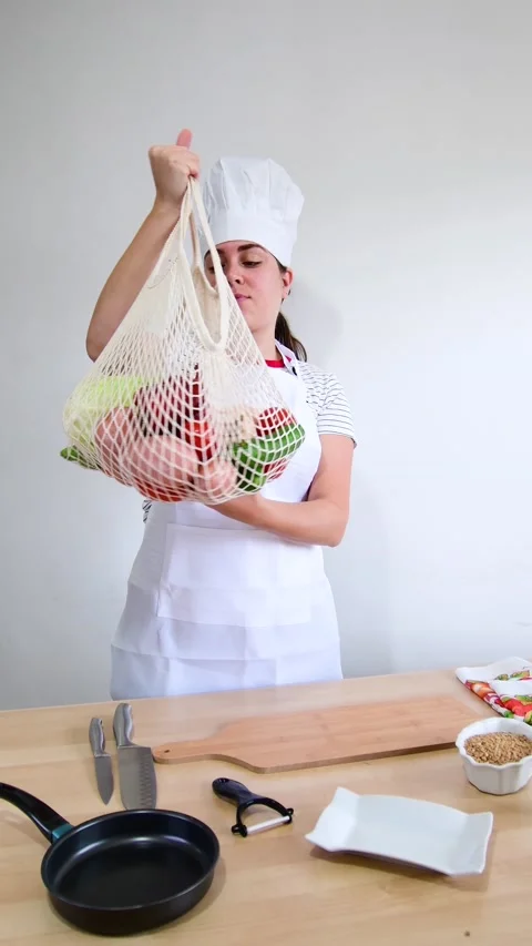 Female cook holding string bag with fresh vegetables. Stock Footage 204660891