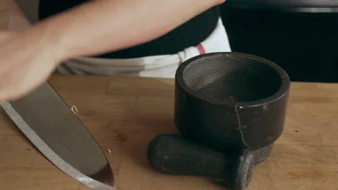 Female cook preparing garlic using mortar and pestle for an octopus carpaccio di Stock Footage 199463499