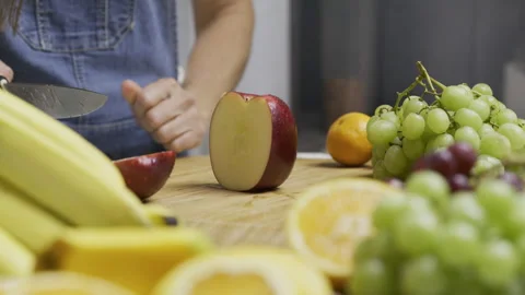 Female cook slicing through apple with sharp knife on cutting board with Stock Footage 341220629