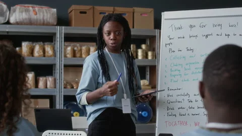Female Coordinator Discussing Work with Team in Volunteers Center Stock Footage 310355944