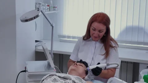 Female cosmetologist performs RF lifting procedure on a client Stock Footage 337737907