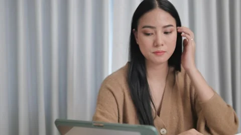 A female creator taking notes sitting at home in front of a tablet  Stock Footage 197481093